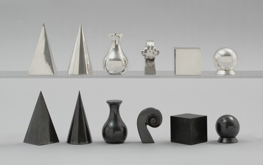 The image shows two rows of geometric shapes. The top row includes a metallic pyramid, cone, vase, gear, cube, and sphere, while the bottom row has black versions of a pyramid, cone, vase, spiral, cube, and sphere. This is an AI generated description. To give feedback, email ai@moma.org.